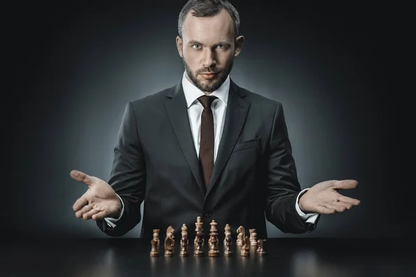 Businessman sitting at table with chess pieces — Stock Photo