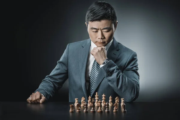 Азиатский бизнесмен и шахматные фигуры — стоковое фото