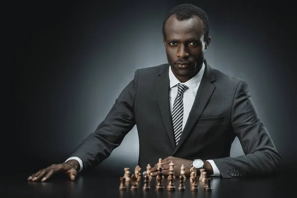 Hombres de negocios afroamericanos y figuras de ajedrez - foto de stock