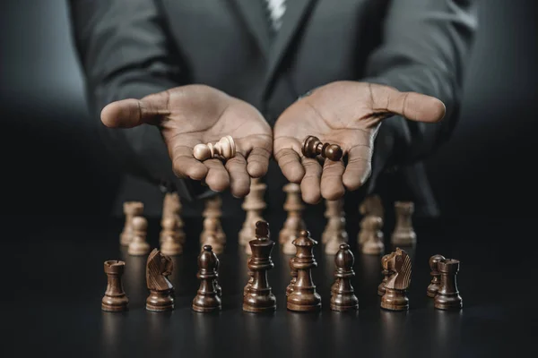 Africano americano empresário segurando figuras de xadrez — Fotografia de Stock