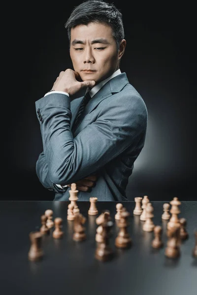 Hombre de negocios asiático y piezas de ajedrez - foto de stock