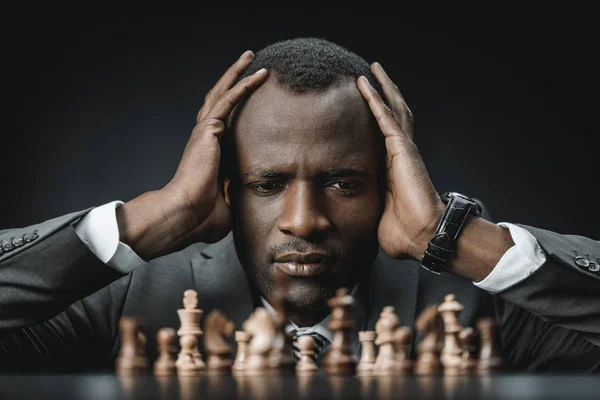 Confuso hombre de negocios afroamericano con ajedrez - foto de stock