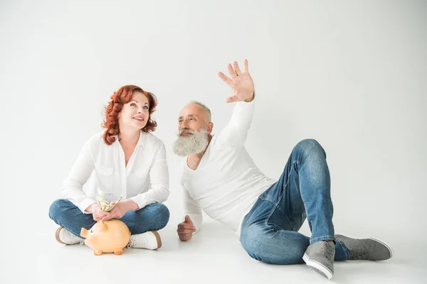 Casal com dólares e banco porquinho — Fotografia de Stock