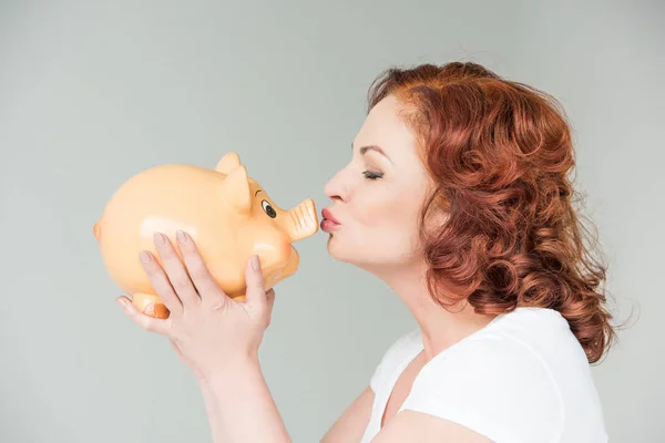 Woman kissing piggy bank — Stock Photo