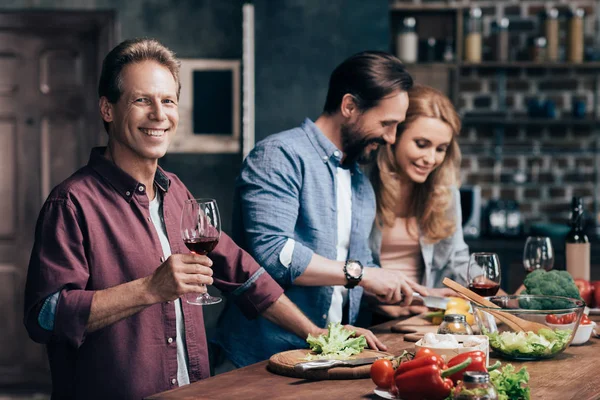 Friends drinking wine while cooking dinner — Stock Photo
