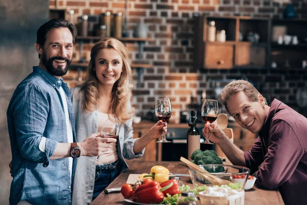 Friends drinking wine while cooking dinner — Stock Photo