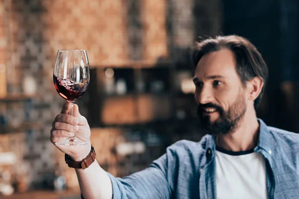 Hombre examinando el vino tinto - foto de stock