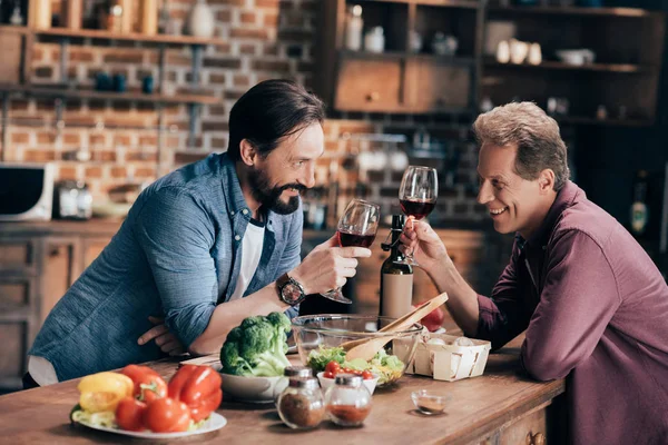 Hombres bebiendo vino en la cocina - foto de stock