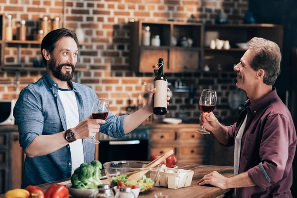 Hombres bebiendo vino en la cocina - foto de stock