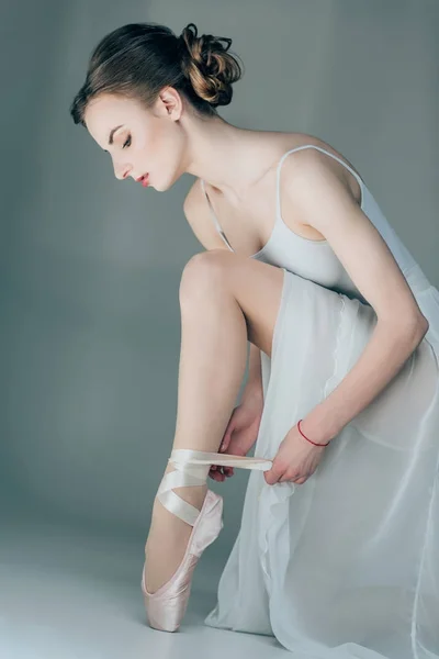 Балерина в балетных туфлях на ногах, изолированная на сером — стоковое фото