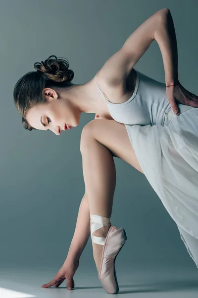 Jovem bailarina em vestido branco alongamento em estúdio — Fotografia de Stock