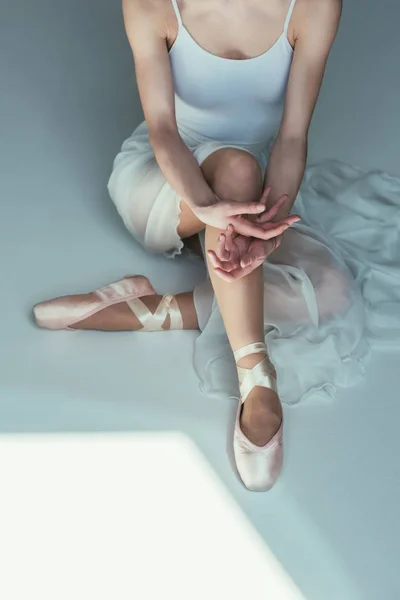 Vue recadrée de l'élégante ballerine assise en robe blanche et chaussures de ballet — Photo de stock