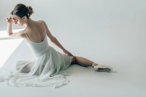 Visão traseira da bailarina elegante sentado em vestido branco e sapatos de balé — Fotografia de Stock