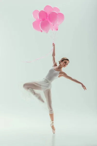 Bailarina de ballet en vestido blanco bailando con globos rosados, aislada en blanco - foto de stock