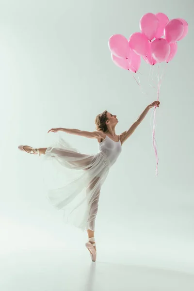 Ballerina in white dress dancing with pink balloons, isolated on white — Stock Photo