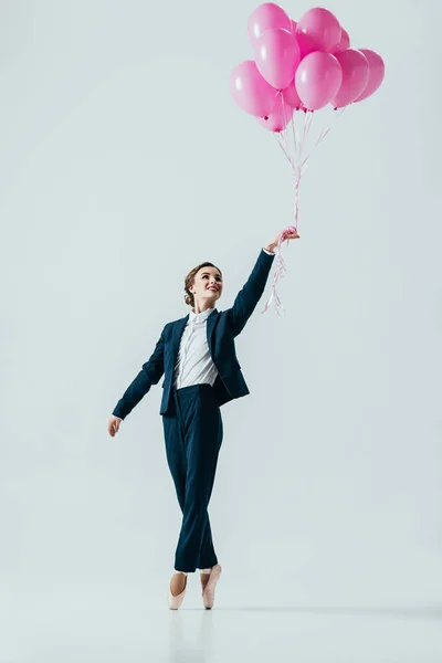 Businesswoman in suit and ballet shoes holding pink balloons, isolated on grey — Stock Photo