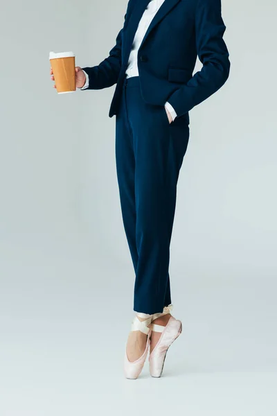 Cropped view of businesswoman in ballet shoes holding coffee to go, isolated on grey — Stock Photo