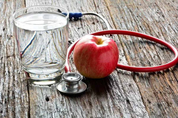 Werkzeuge Arzt ein Stethoskop hinter einem Apfel- und Wasserglas für h — Stockfoto