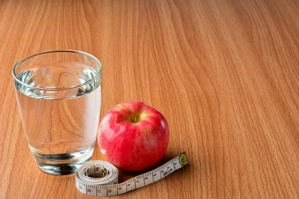 Ruban à mesurer, pomme et verre d'eau pour un corps sain et mince — Photo