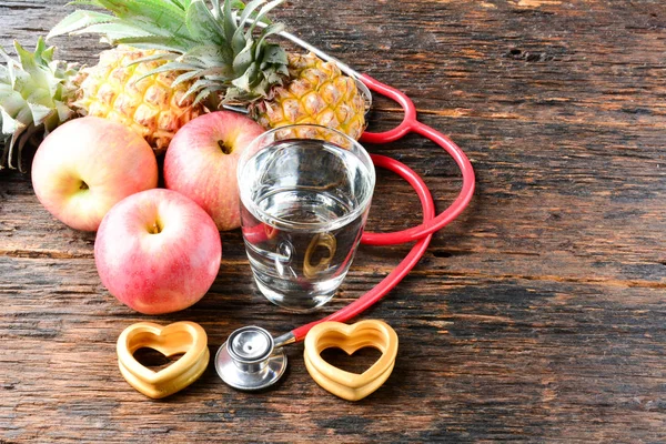 Fruta, corazón, estetoscopio y vaso de agua para la salud y el cuerpo s — Foto de Stock