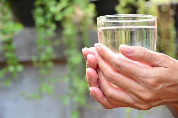 Hands hold the glass and water in glass on nature background — Stock Photo, Image