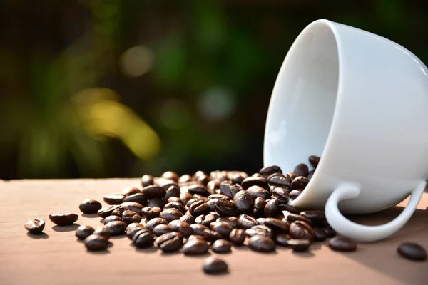 Grãos de café em copo branco na mesa de madeira — Fotografia de Stock