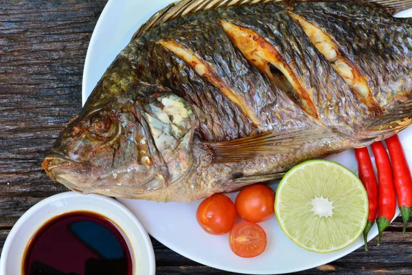 Biber biber, limon ve domates ile beyaz plaka üzerinde ızgara balık 