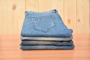 Mavi jeans katlanmış yığın ahşap masa ve ahşap arka plan