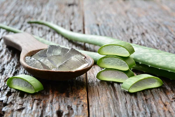 Aloe gel on wooden spoon with aloe sliced on wooden table. — Stock Photo, Image