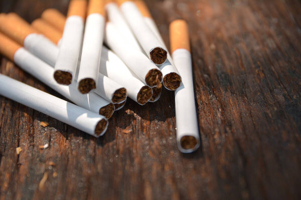Tobacco cigarettes on wooden background with light shines