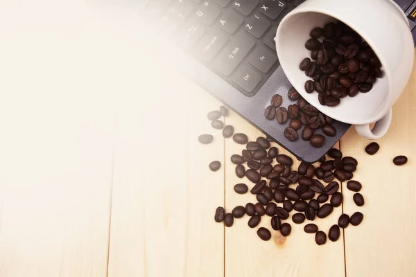 Eine Tasse Kaffee auf den Tisch stellen und Kaffeebohnen verteilen — Stockfoto