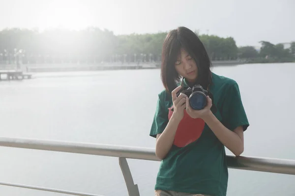 Mujer joven sonriente usando una cámara para tomar fotos al aire libre —  Fotos de Stock