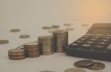 siyah hesap makinesi ile para ve başka bir sikke yığını. Finansal