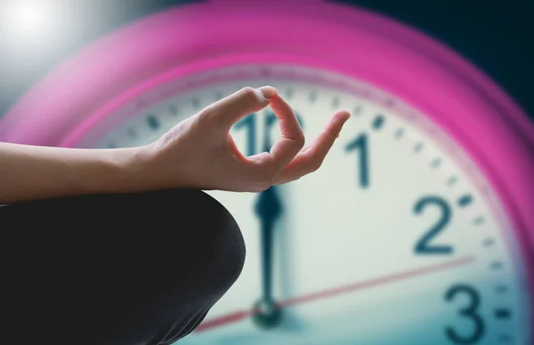 Primer plano de brazos femeninos y masculinos y piernas cruzadas durante la meditación con fondo de reloj. — Foto de Stock