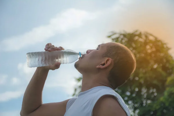 Gros plan d'un homme buvant de l'eau d'une bouteille après l'exercice. Portrait d'un homme buvant une eau à l'extérieur . — Photo