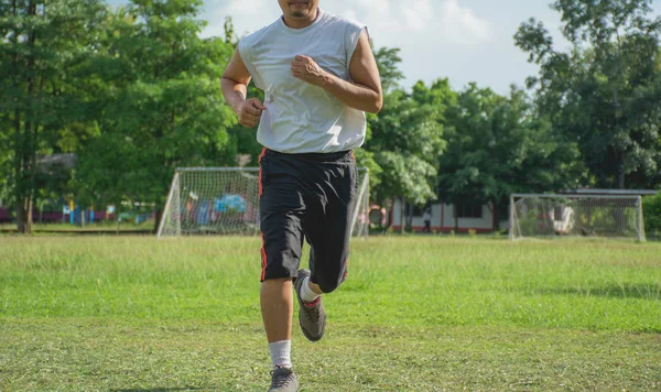 Man running in grass field for exercise. Healthy lifestyle. Handsome man running on grass field in morning