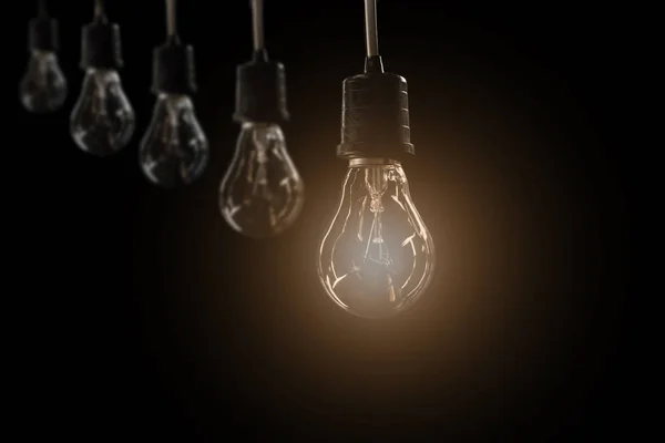 Lampadine a sospensione con lampadine luminose su sfondo scuro. Idea e concetto di creatività con lampadine . — Foto Stock
