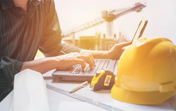 Építész mérnök használ laptop dolgozó sárga bukósisak, a laptop és a kávéscsésze a táblázat. — Stock Fotó