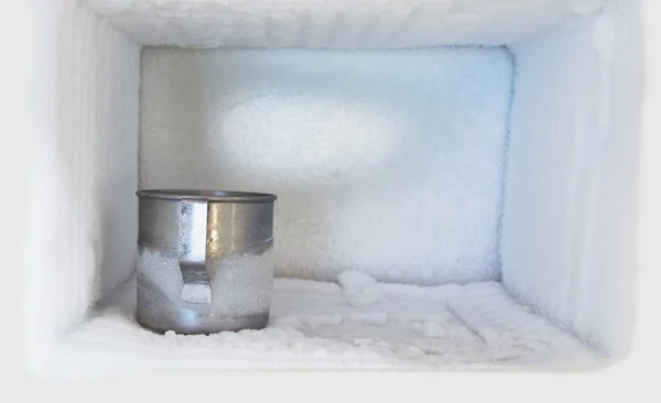 Vaso de agua potable de acero inoxidable en el congelador de un refrigerador. Acumulación de hielo dentro de las paredes de un congelador. — Foto de Stock