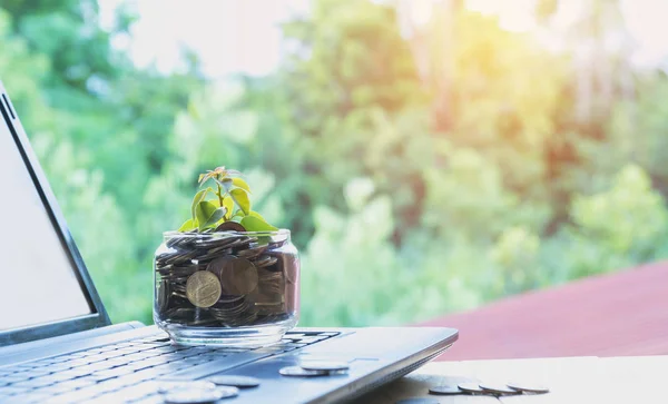 Munten zetten in glas en stapel munten met laptop voor groeiende bedrijven en belasting seizoen. — Stockfoto