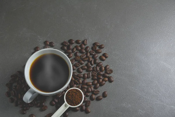 Granos de café y café en taza blanca sobre mesa negra . — Foto de Stock