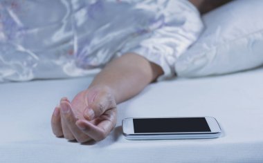 Yatak Odası, yatakta bir cep telefonu ile uyuyan kadın gözleri kapalı dinleniyor.