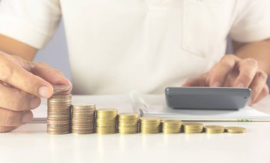 Adamın elini tuşuna basarak hesap makinesi yığın paralar ile masaya. Hesap makinesi düğmesine basarak adam. Finansal analiz kavramı.