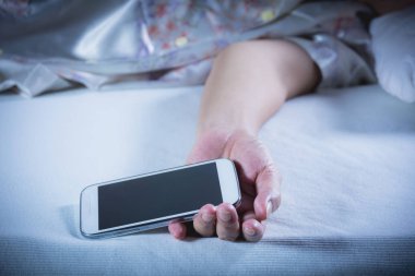 Yatak Odası, yatakta bir cep telefonu ile uyuyan kadın gözleri kapalı dinleniyor.