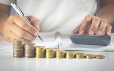 Adamın elini tuşuna basarak hesap makinesi yığın paralar ile masaya. Hesap makinesi düğmesine basarak adam. Finansal analiz kavramı.