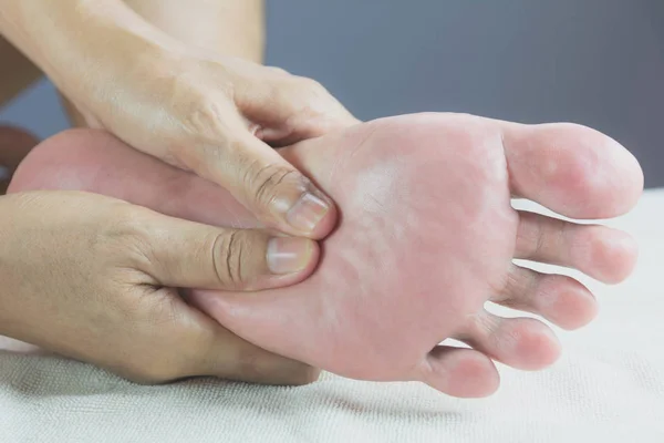 Close-up of foot massage in the salon of a physiotherapist on a white bed. — Stock Photo, Image