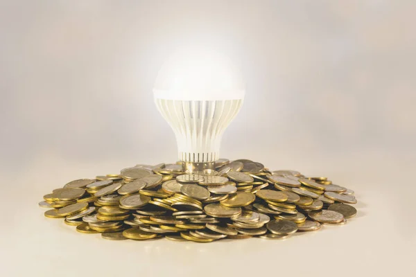 Energy saving light bulb and surrounding by stacks of coins. Financial, saving and idea concept. — Stock Photo, Image