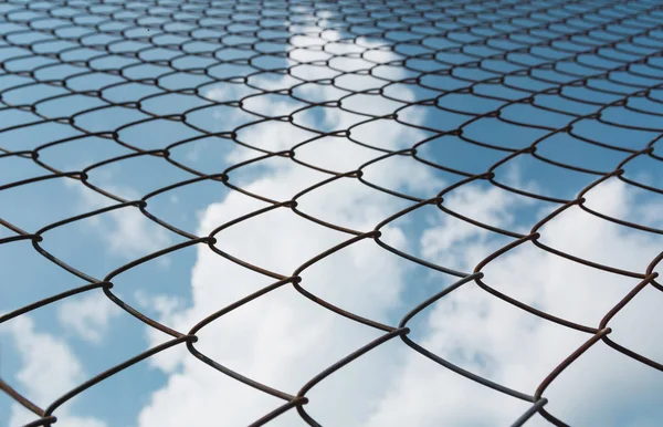 Rusty chain link fence under the sky background. Abstract closeup of a chain link sky background.