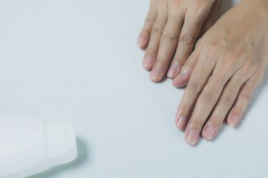 el losyonu şişesi üzerinde beyaz masa arka plan ile genç kadın