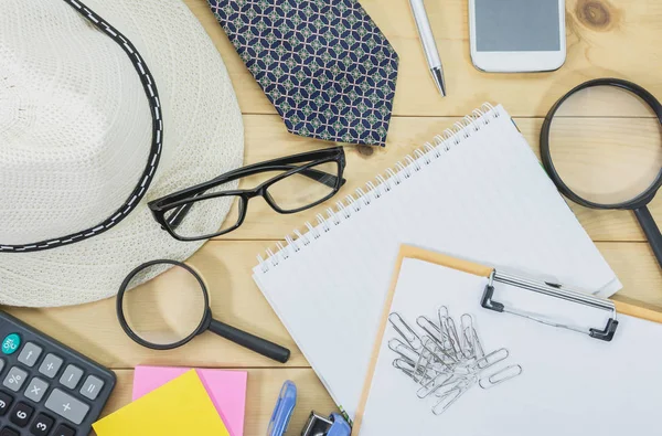 Office table top view with the glasses, note book, magnifying glass and mobile phone on desk cluttered. Cluttered office desk background.